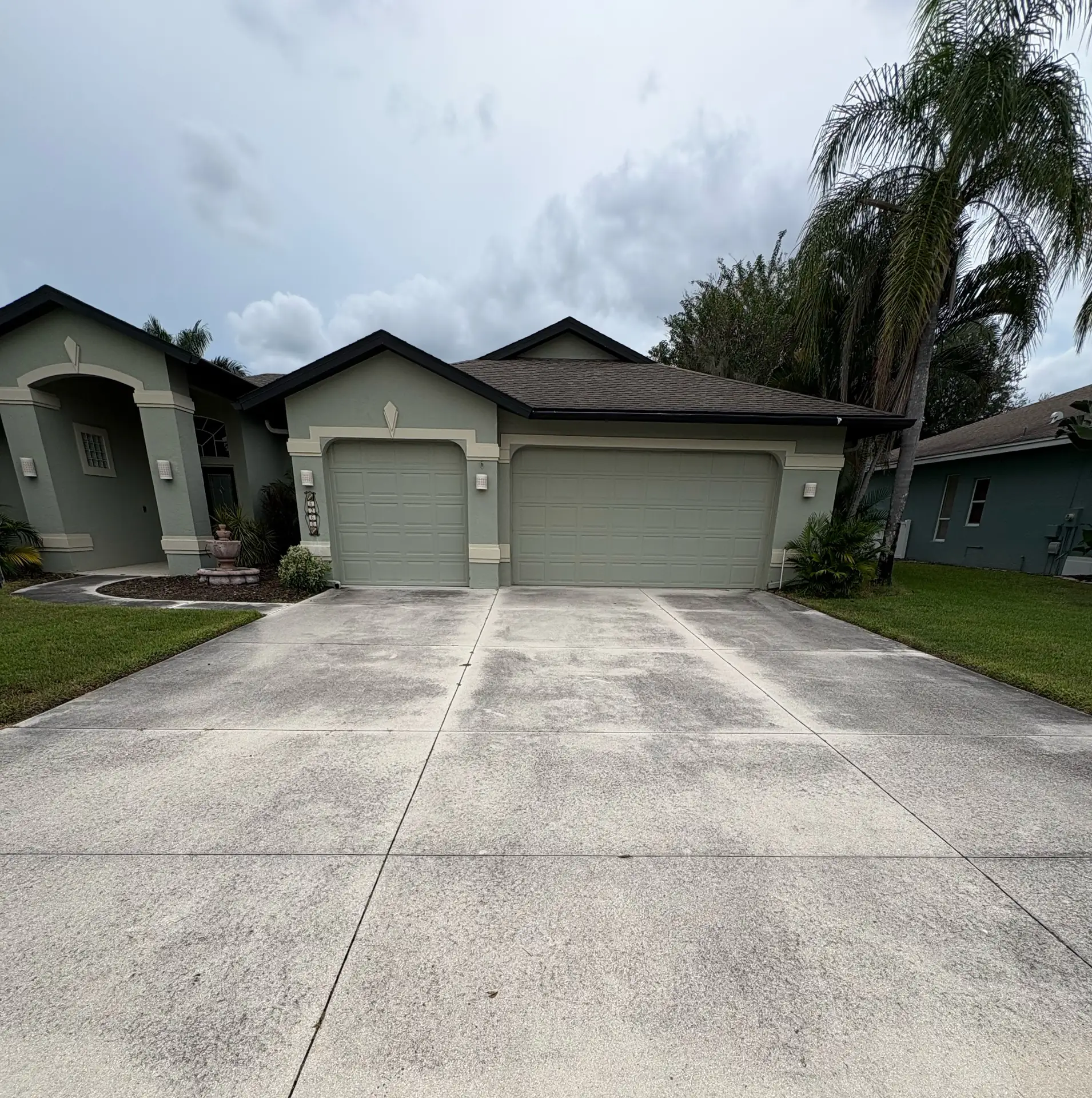 A stained concrete driveway in front of a two car garage, under a cloudy sky