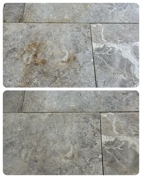 Top and bottom comparison of grey marble tile, rust coloured stain above and a much cleaner tile below