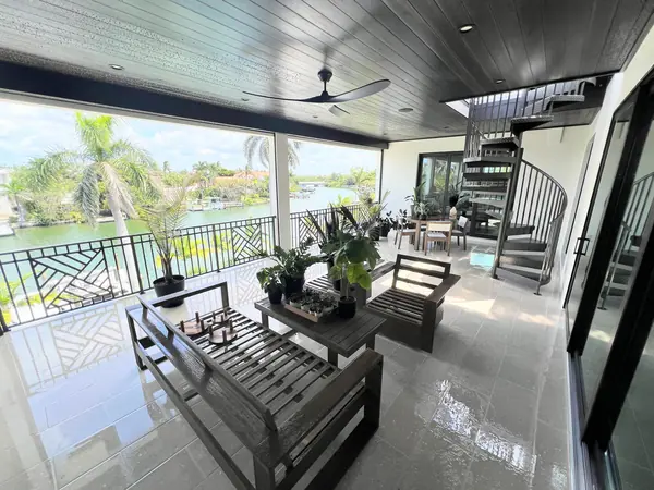 Covered upper balcony with a wet looking stone tile floor, wooden outdoor furniture, spiral stair and waterway view