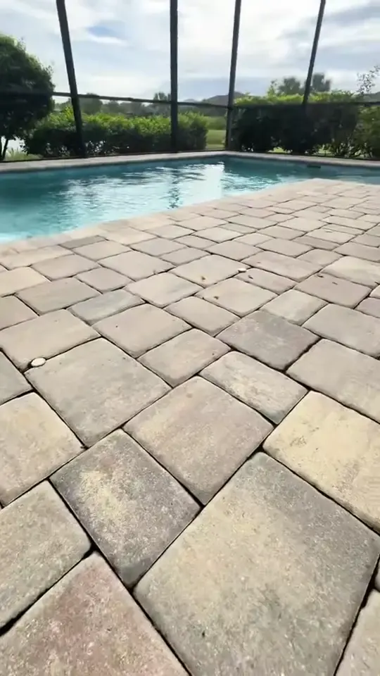Hose and surface cleaner on stained pool deck pavers, then sealer rolled on.